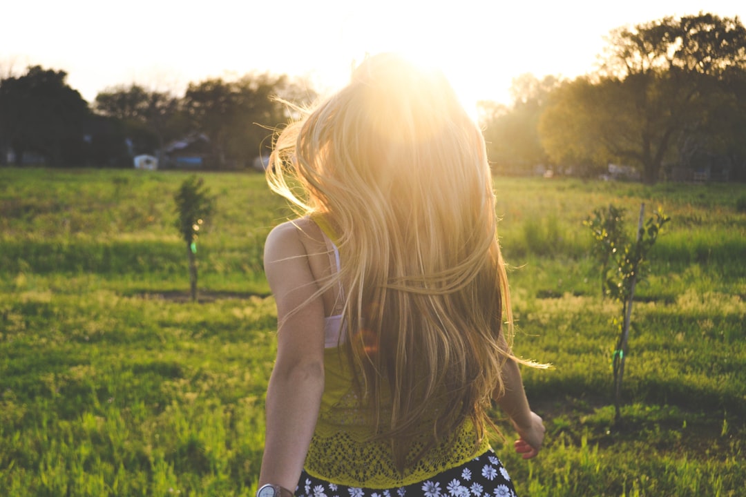 Sunlight welcomes blonde girl by Purse Brands woman walking on lawn with trees